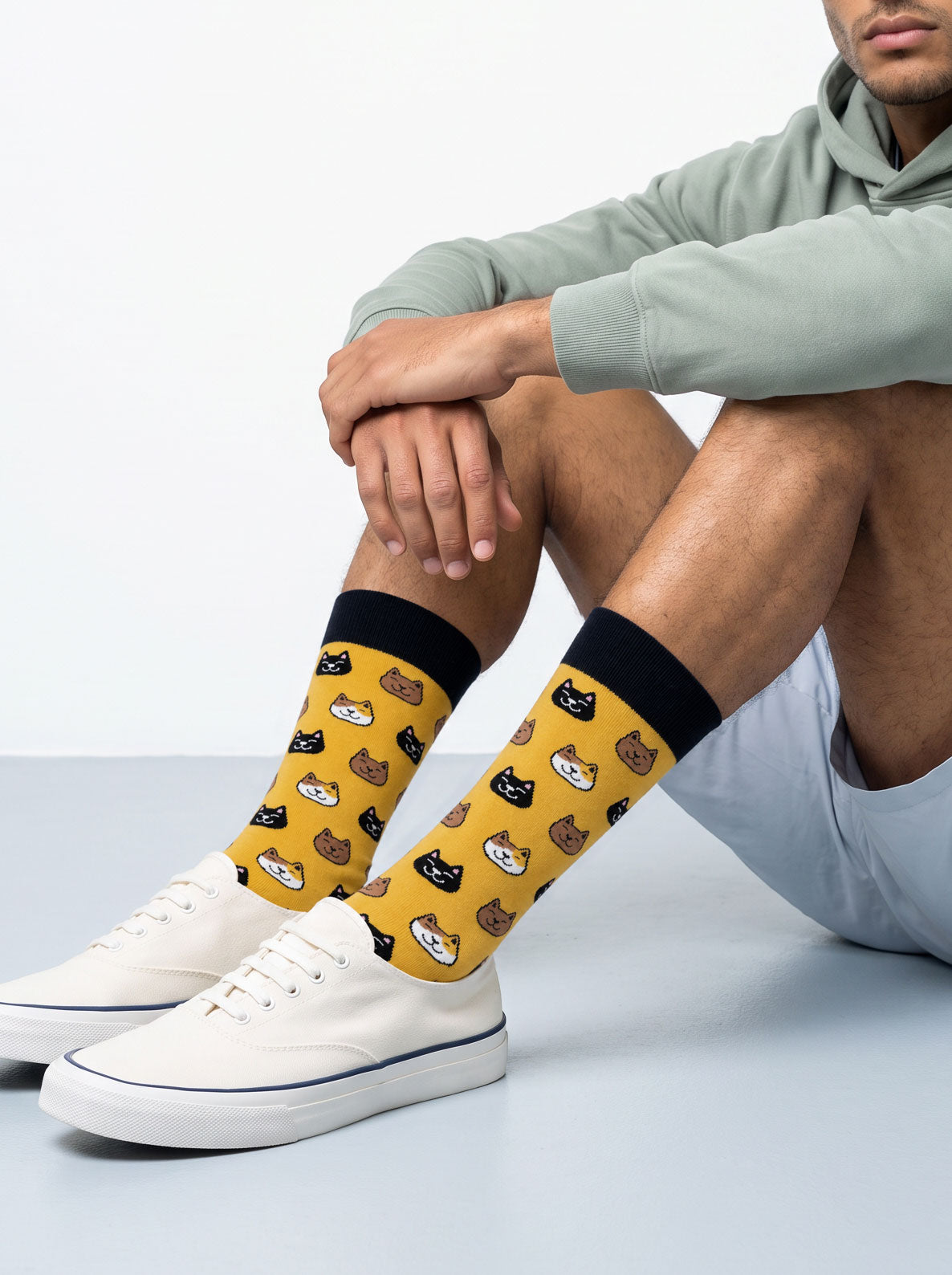 Man wearing yellow cat socks with white trainers