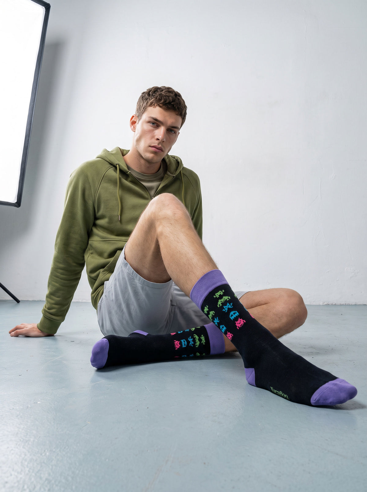 Man in a hoodie wearing black pixel alien bamboo socks