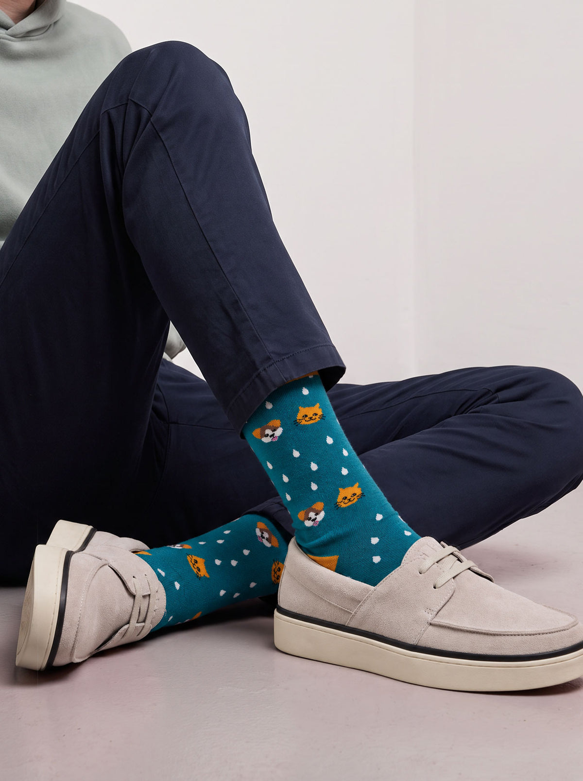 Man in navy trousers wearing teal cats and dogs socks