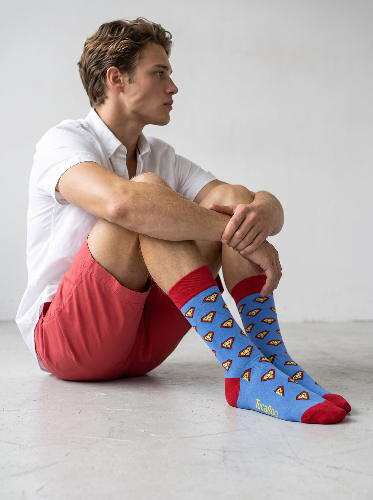 Man in red shorts wearing blue superhero shield socks