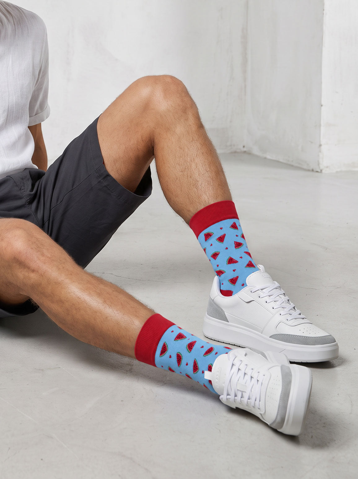 Man wearing light blue watermelon socks with white trainers